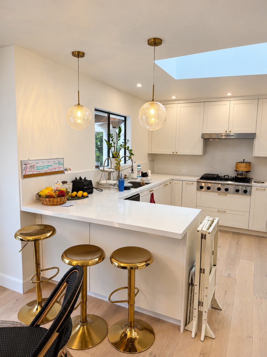 White kitchen with warm pendant lights and gold stools